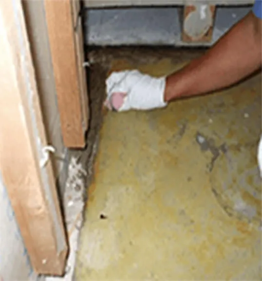 床のごみをヘラで削り取る様子