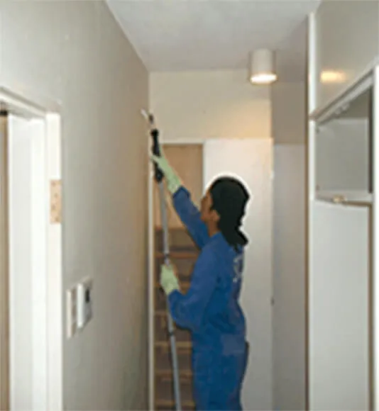 壁に器具を用いて処置する職員